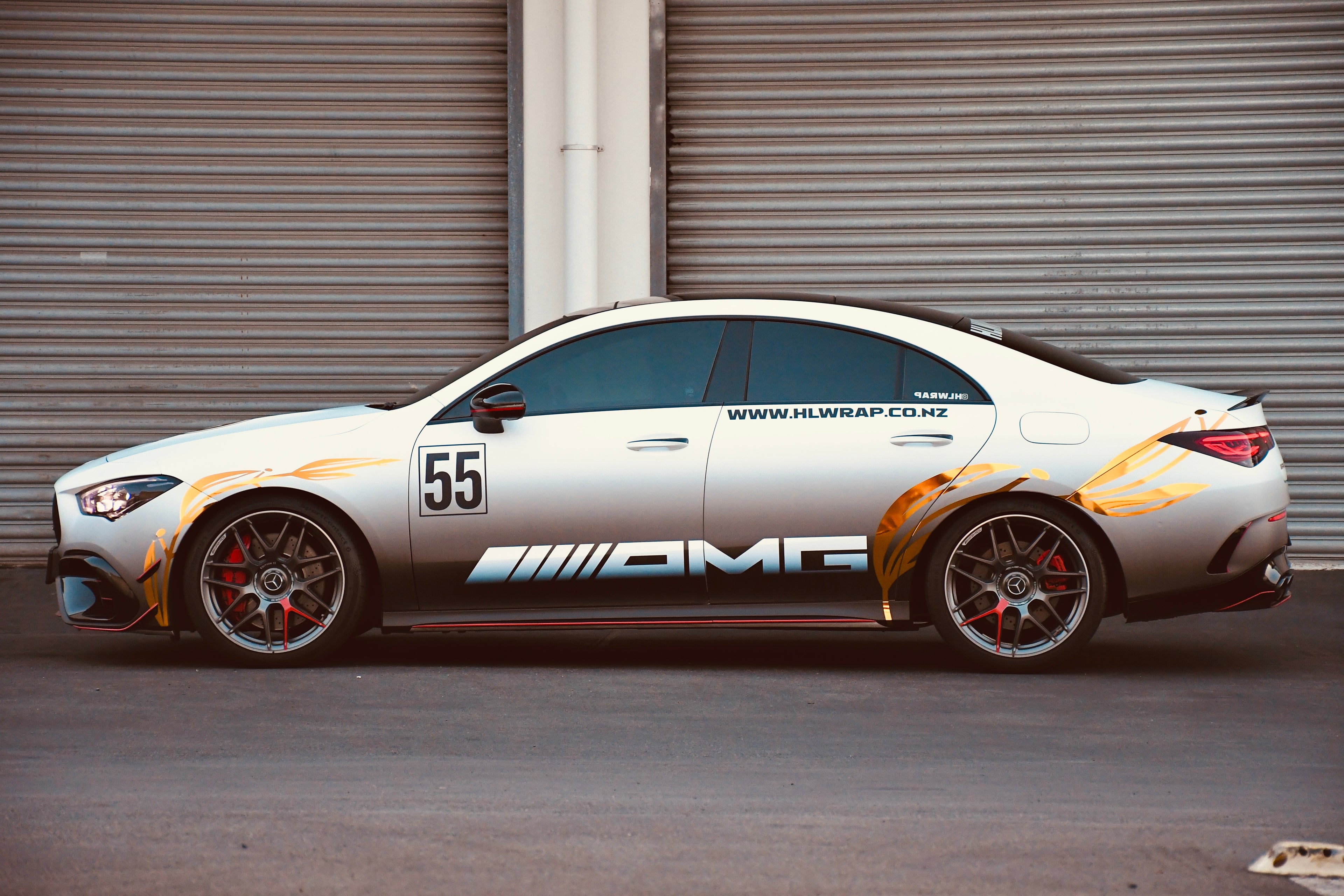 Car with AMG branding and racing number 55 parked in front of a metallic shutter.
